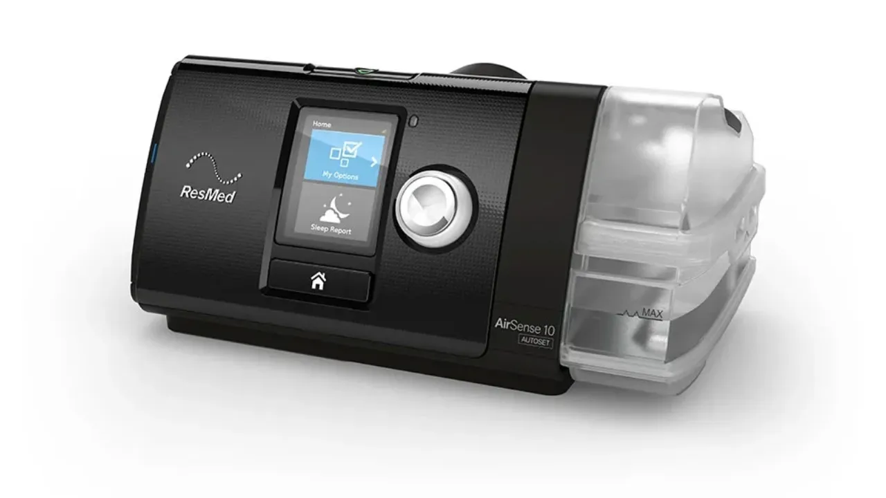 CPAP ResMed AirSense 10 AutoSet com a câmara de água do umidificador acoplada do lado direito, mostrando a tela com o menu Minhas Opções e o botão giratório