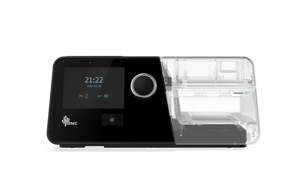 Aparelho de CPAP BMC G3 visto de frente, com a tela e o botão giratório à esquerda e a câmara de água do umidificador encaixada à direita